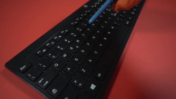 Person in Handschuhen reinigt Tastatur mit Luftstaubgebläse auf Rot — Stockvideo
