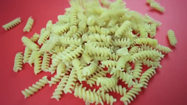 Trozos de pasta fusilini sin cocer caen en un montón de rosa — Vídeos de Stock