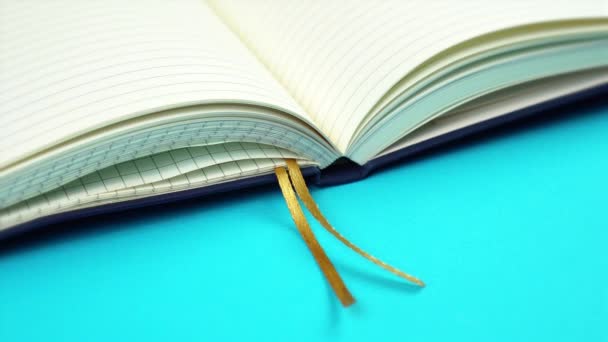 Notebook com páginas em branco e borlas douradas em azul claro — Vídeo de Stock