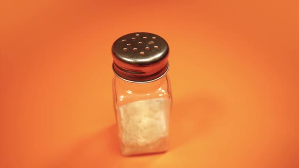 Modern salt shaker with metal cap on orange background — Stock Video