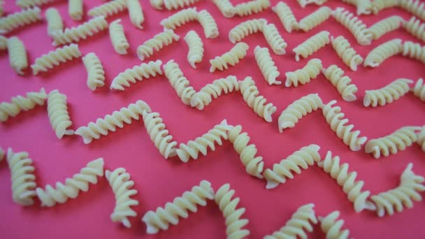 Ongekookte fusilini pasta stukken op helder roze achtergrond — Stockvideo