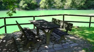 Dağlardaki gölün önünde piknik masası.