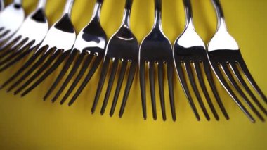 Parlak sarı arkaplanda gümüş çatal koleksiyonu