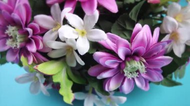 Açık mavi arkaplanda suni çiçeklerin etrafında hareket