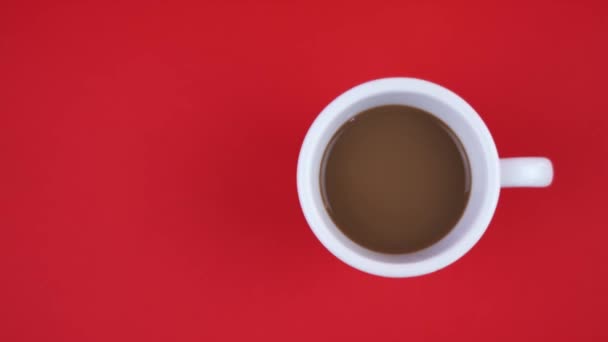 Kırmızı arka planda tasarlamak için bir fincan lezzetli kahve ve alan — Stok video