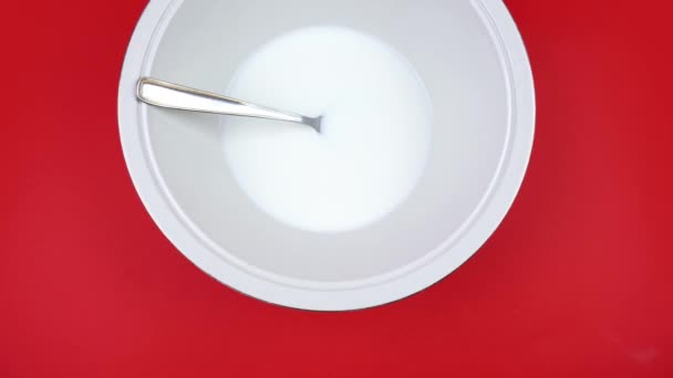 Bowl with natural yogurt and silver spoon on red background — Stock Video