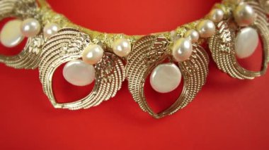 Kırmızı arka planda mücevherleri olan altın taç.