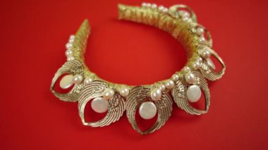 Kırmızı arka planda mücevherleri olan altın taç.