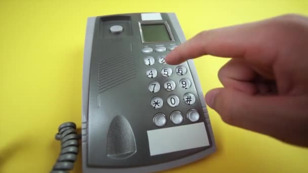 Man wijzerplaten nummer op bekabelde telefoonbasis op gele achtergrond — Stockvideo