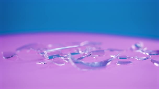 Кусочки разбитого стекла на розовом столе — стоковое видео