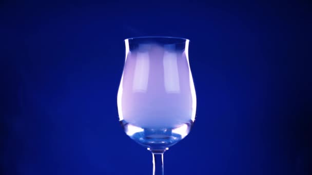 Bicchiere di vino pieno di fumo che scorre su sfondo blu scuro — Video Stock