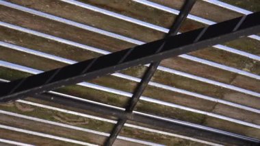 Güneşli bir günde ağaçların ahşap çatısı altında direkli hareket