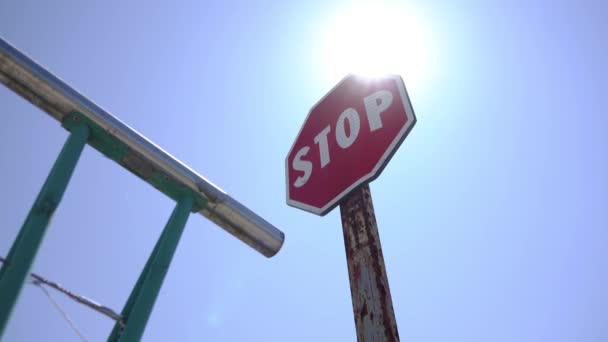 Красный дорожный знак Остановка на ржавом столбе рядом с металлическими перилами крупным планом — стоковое видео