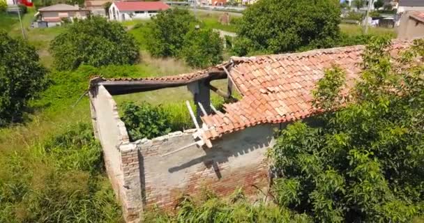 Старый амбар с разрушенной черепичной крышей в зеленом заброшенном саду — стоковое видео