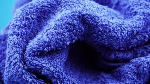Küçük kıvrımlı mavi kumaş havlusu yalanlar ve döndürür — Stok video