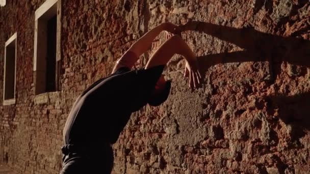 Balet tancerz stanowi stojąc w pobliżu zabytkowego budynku ściany — Wideo stockowe