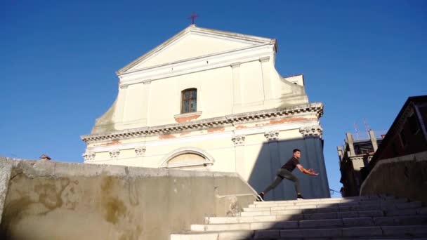 Guy dansar på vintage trappor mot historiska kyrkan och himlen — Stockvideo