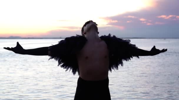 Chico en traje diseñado de plumas posa contra el río — Vídeos de Stock