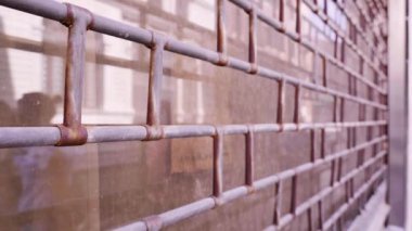 Mermer binanın eski çitleri, hareket eden insanların siluetleri.