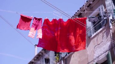 Kırmızı çamaşırlar yol üzerindeki eski binanın ipinde kuruyor.