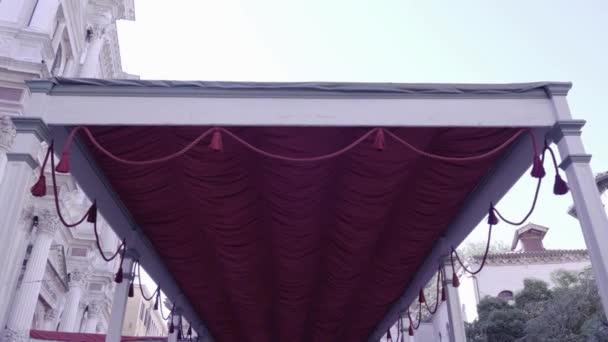 Toldo de terciopelo rojo con borlas en columnas blancas en la calle — Vídeos de Stock