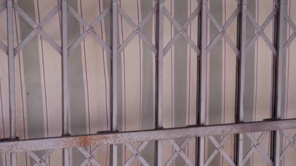 Old rusty metal grate gate and striped fabric on building — Stock Video