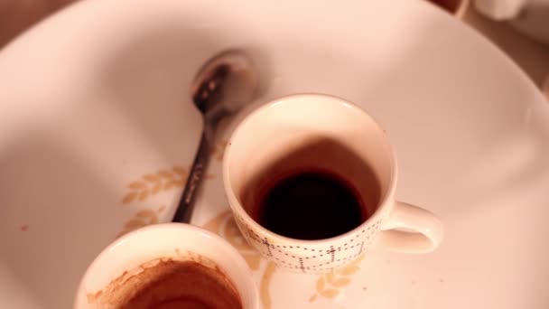 Schwarzer Espresso in kleiner dekorierter Kaffeetasse auf weißem Teller — Stockvideo