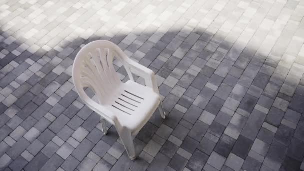 Cadeiras de plástico branco colocar em pilha na calçada pavimentada cinza — Vídeo de Stock