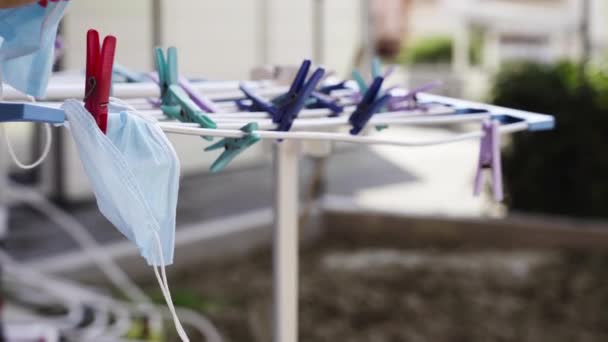 Hand repareert blauwe gezichtsmaskers met wasknijpers op droogrek — Stockvideo