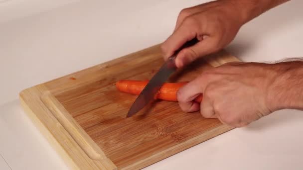 Człowiek ręce obierać pomarańczową marchewkę na brązowej drewnianej desce timelapse — Wideo stockowe