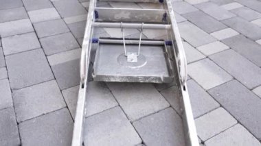 Gri asfalt kaldırımda uzanan büyük metal merdiven.