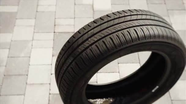 Nuevo neumático negro rueda solo en el primer plano pavimentado gris — Vídeo de stock
