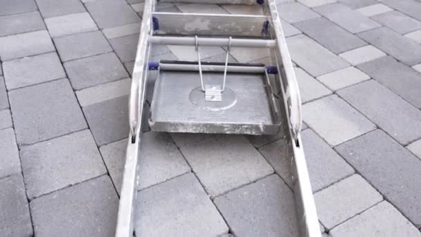 Grote metalen ladder ligt op grijs trottoir close-up — Stockvideo