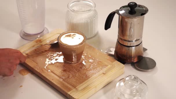 Человек помешивает кофе с молоком в чашке проливая на деревянную доску — стоковое видео