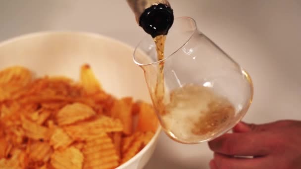 Persoon giet bruin schuimende bier in transparante wijnglazen — Stockvideo