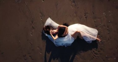 Kumsalda siyah beyaz kumaşla kaplı genç bir kadın.