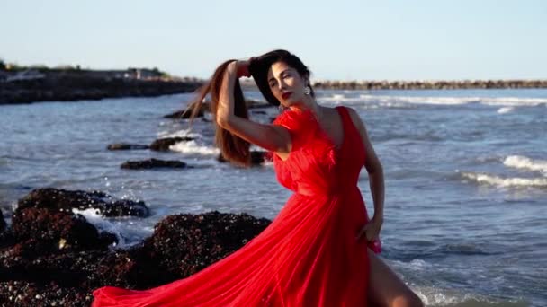 Lady σε κόκκινο φόρεμα με σχισμή θέτει κρατώντας μακριά χαλαρά μαλλιά — Αρχείο Βίντεο