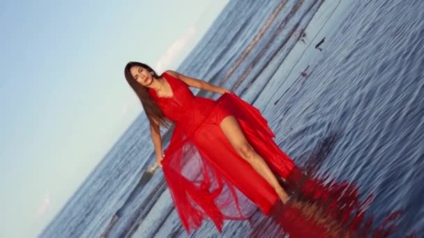 Молода жінка в довгій червоній сукні з мереживною спідницею і щілиною — стокове відео