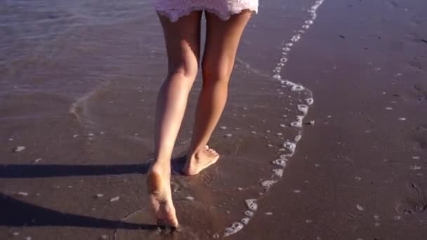 Giovane donna in abito elegante passeggiate lungo la spiaggia di sabbia bagnata — Video Stock