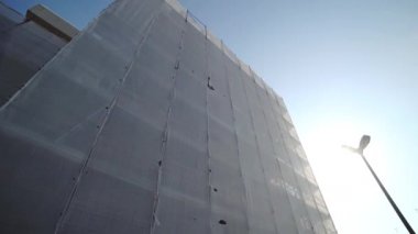 Beyaz koruyucu kumaşla kaplı yapı iskelesi.