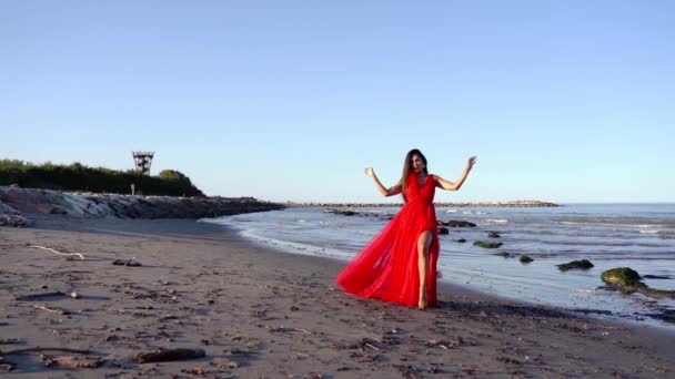 Κομψή μελαχρινή σε μακρύ κόκκινο βραδινό φόρεμα με σχισμή θέτει — Αρχείο Βίντεο