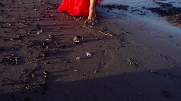 Glückliche barfüßige Brünette im langen roten Kleid spaziert auf nassem Sand — Stockvideo