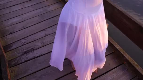 Балерина в длинной юбке танцует на мосту — стоковое видео