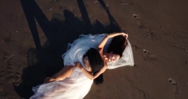 Çıplak göbekli zarif bir bayan ellerini uzun, dağınık saçlarına koyar.