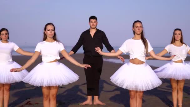 Привлекательные женщины с парнем танцуют балет на пляже океана — стоковое видео