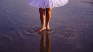 Beyaz etekli bir arkadaşıyla balerin suda dans ediyor.