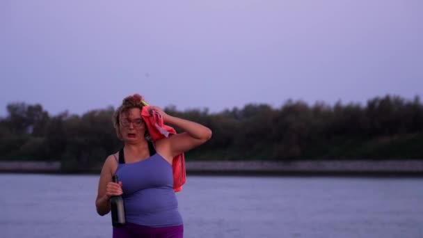 Señora con toallitas con sobrepeso con toalla bebiendo vino en la playa — Vídeos de Stock