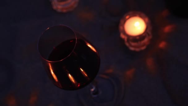 Copo elegante com vinho tinto e pequena vela na praia noturna — Vídeo de Stock