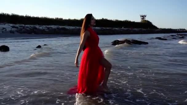 Νεαρή γυναίκα με μακριά μαλλιά μπαίνει στο νερό του ωκεανού — Αρχείο Βίντεο