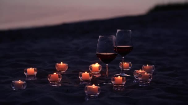 Gece kumsalında mumların yanındaki bardaklara şarap doldurur. — Stok video
